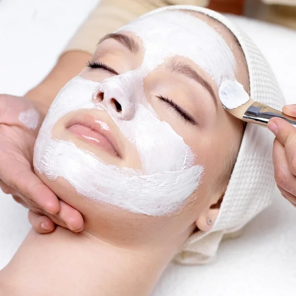 A treatment mask spread across the face during an exfoliating session